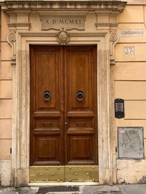 A double wooden door with a brass plate above it, a metal plaque to the right, and a number '27A' on the wall. - Apartment 'Banchivecchi 27' with Wi-Fi and Air Conditioning (Roma)