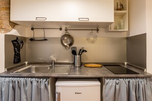 Une cuisine compacte équipée d’un évier, d’une machine à café et d’un petit réfrigérateur.