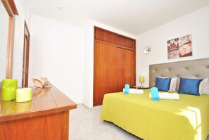 A hotel room with a bed, a desk, and a wooden wardrobe.