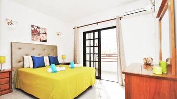 A hotel room with a bed, a nightstand, a dresser, a mirror, and a view of the outside.