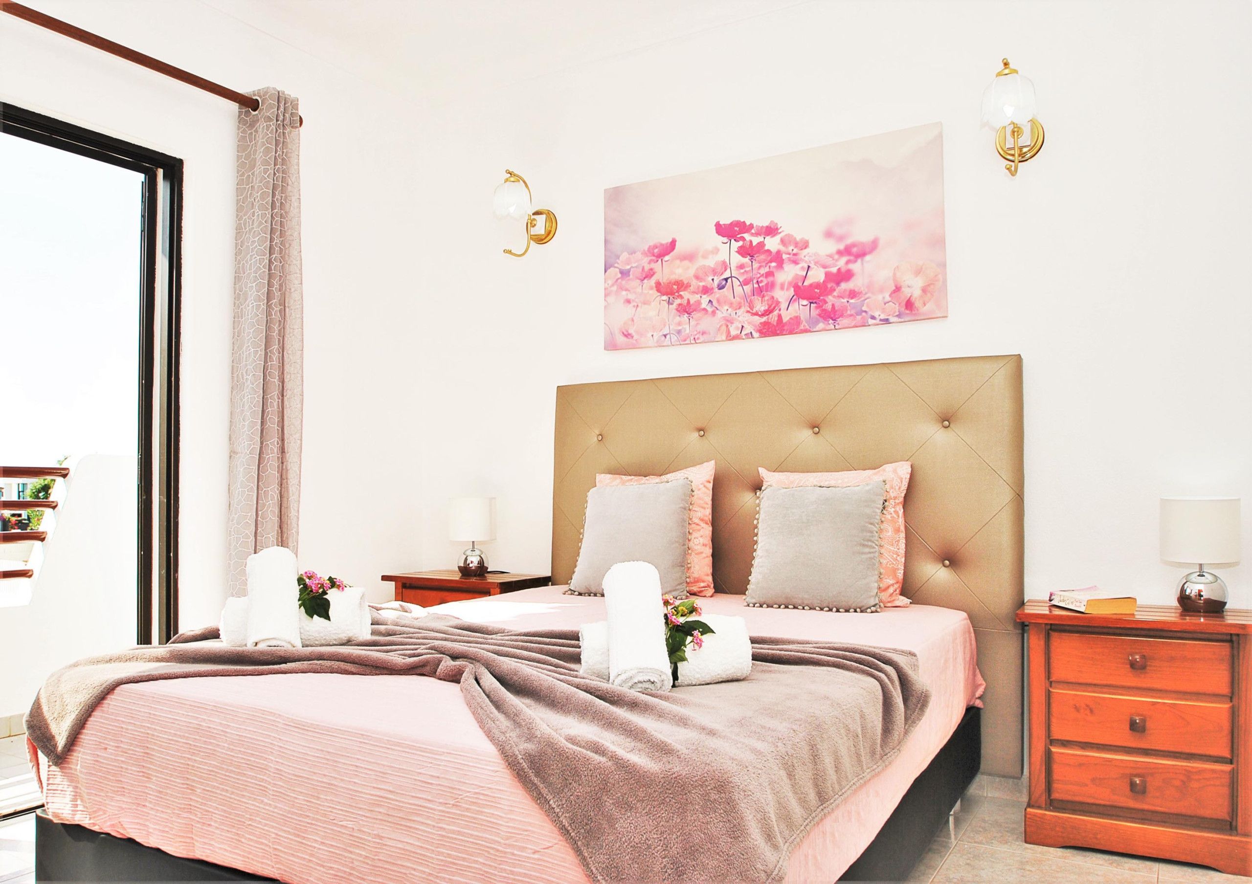 A bedroom with a bed, bedside tables, a headboard, and a wall-mounted picture.