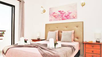 A bedroom with a bed, bedside tables, a headboard, and a wall-mounted picture.