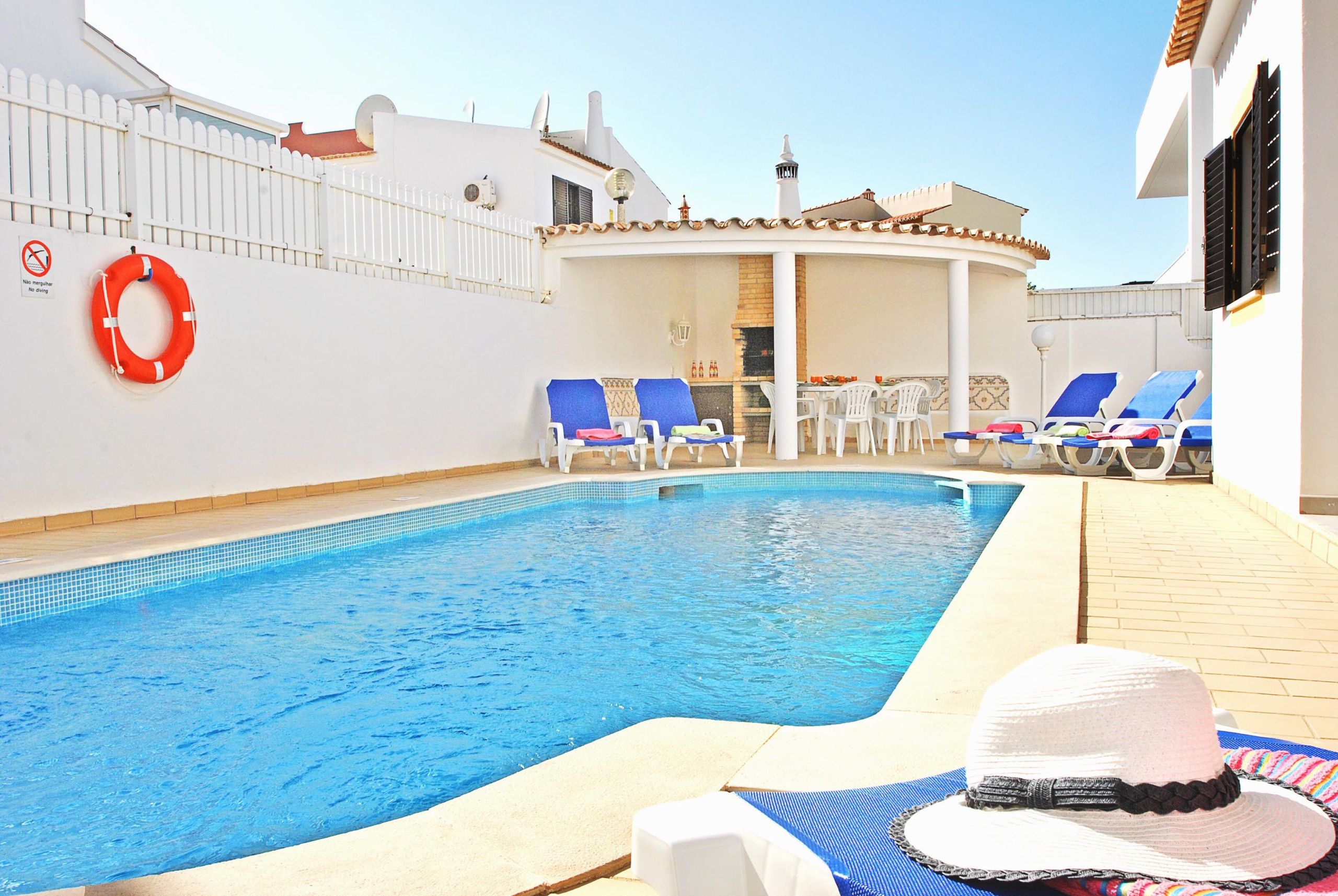 A swimming pool with lounge chairs and a life ring on the wall.