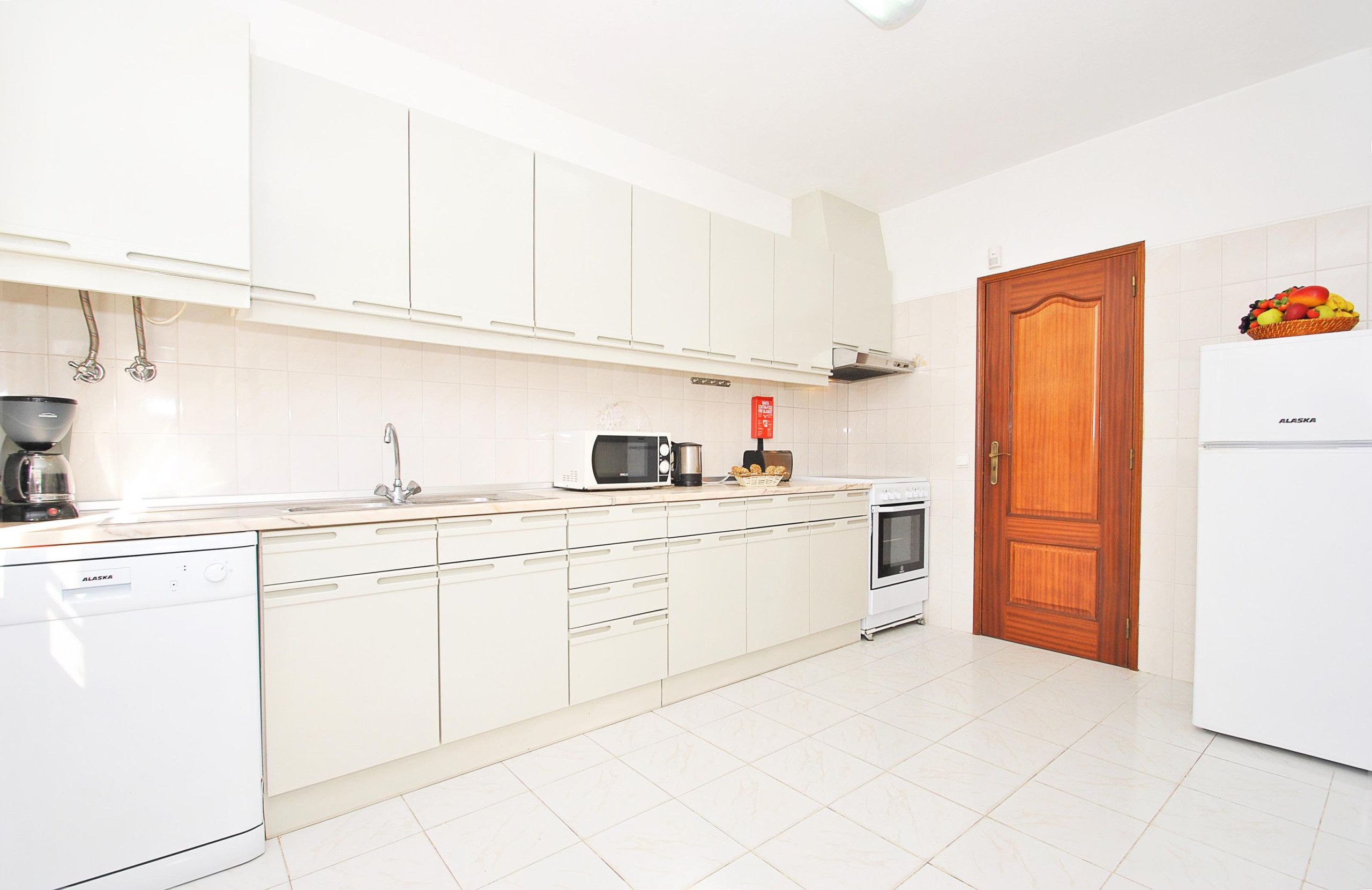 A kitchen with white cabinets, a microwave, a coffee maker, and a refrigerator.