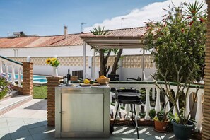 A patio area with a grill, a small table, and a potted plant. - Villa Garden | Pool | Billiard | BBQ | Fireplace (Vélez-Málaga)