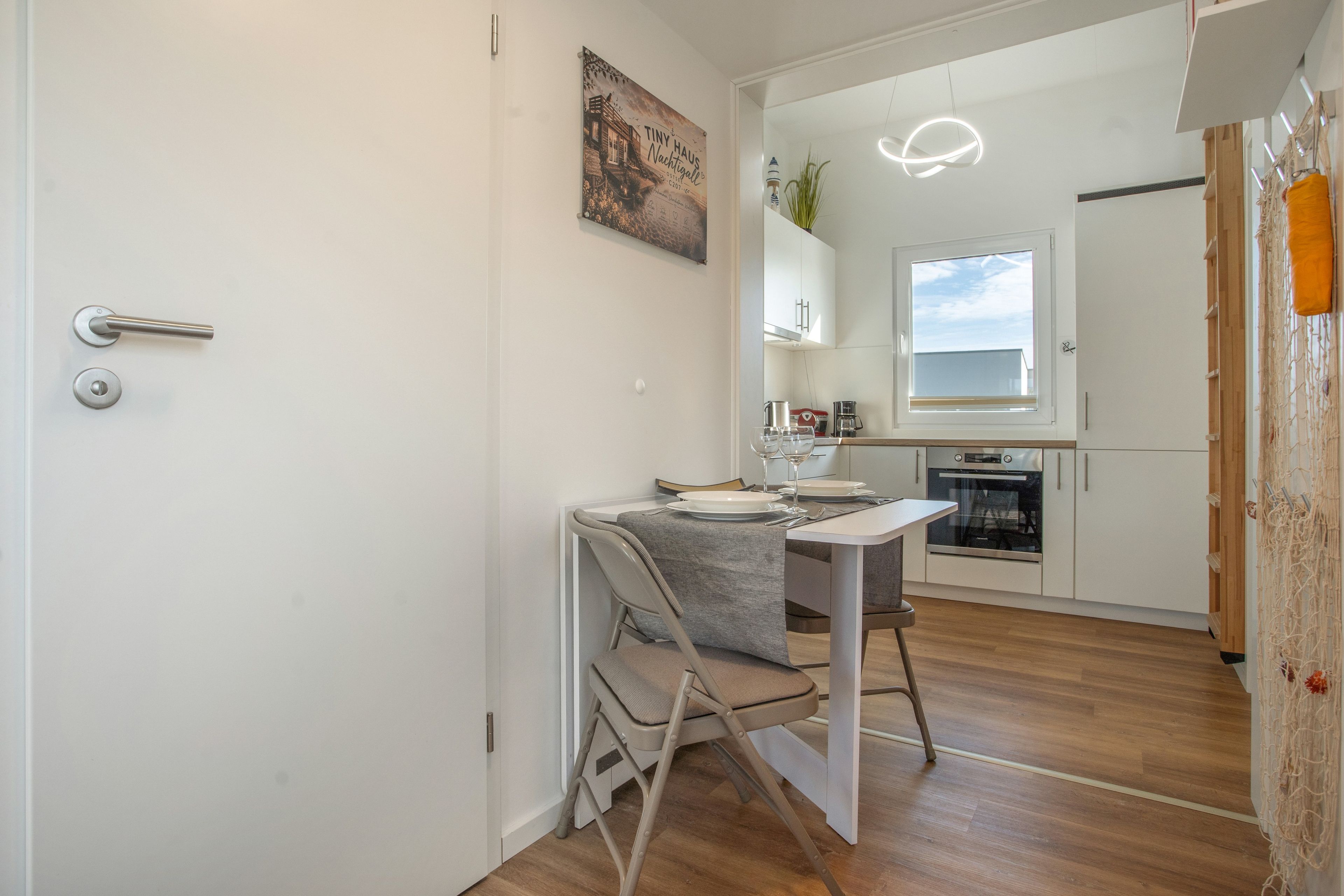 A modern kitchen with white cabinets, a built-in oven, and a window above the sink.