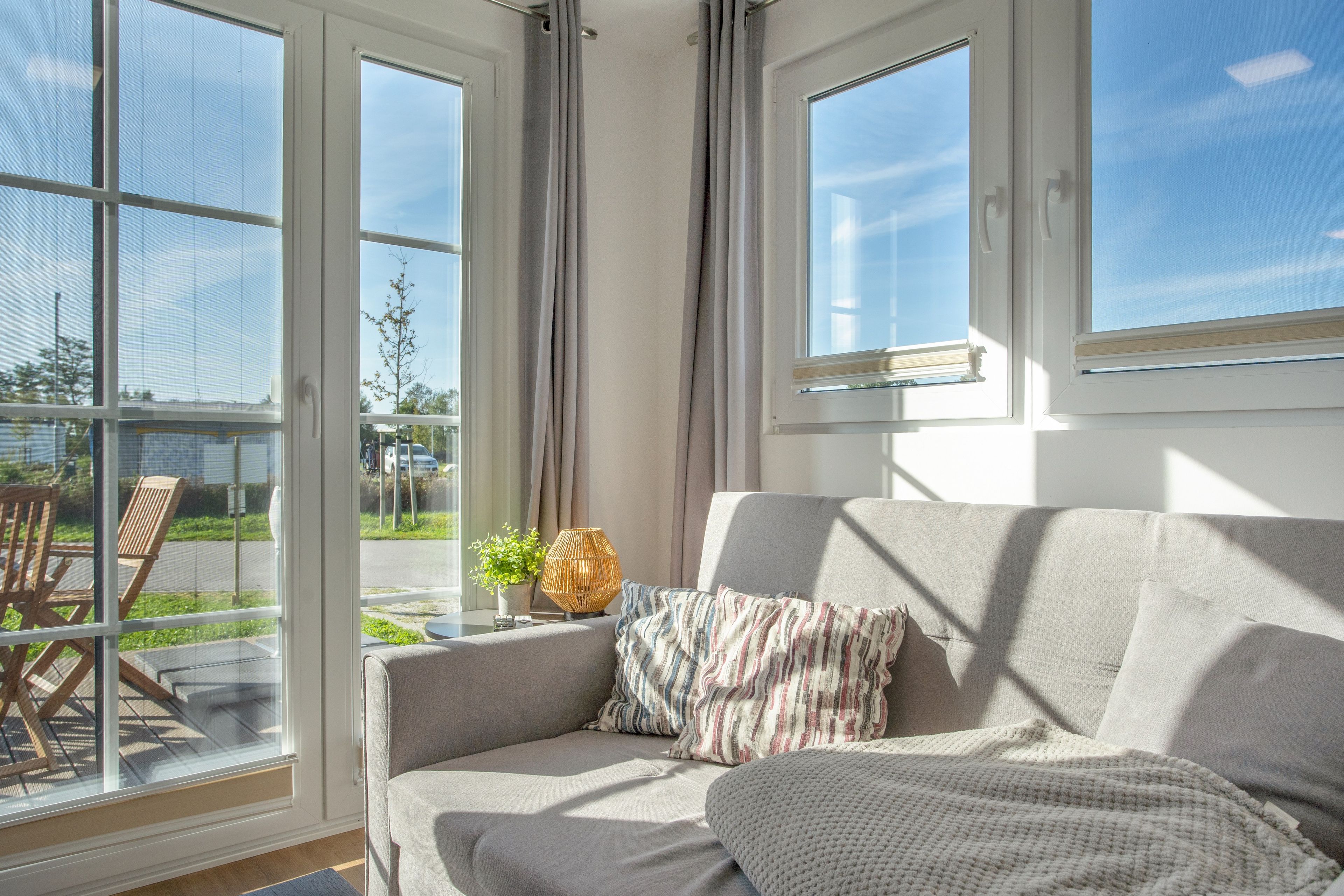 A room with a sofa, a window, and a view of the outside.