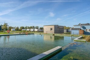 A swimming pool with a clear view of the surrounding area, including a building and a row of mobile homes.
