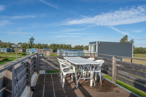 A deck with a table and chairs, overlooking a row of mobile homes.