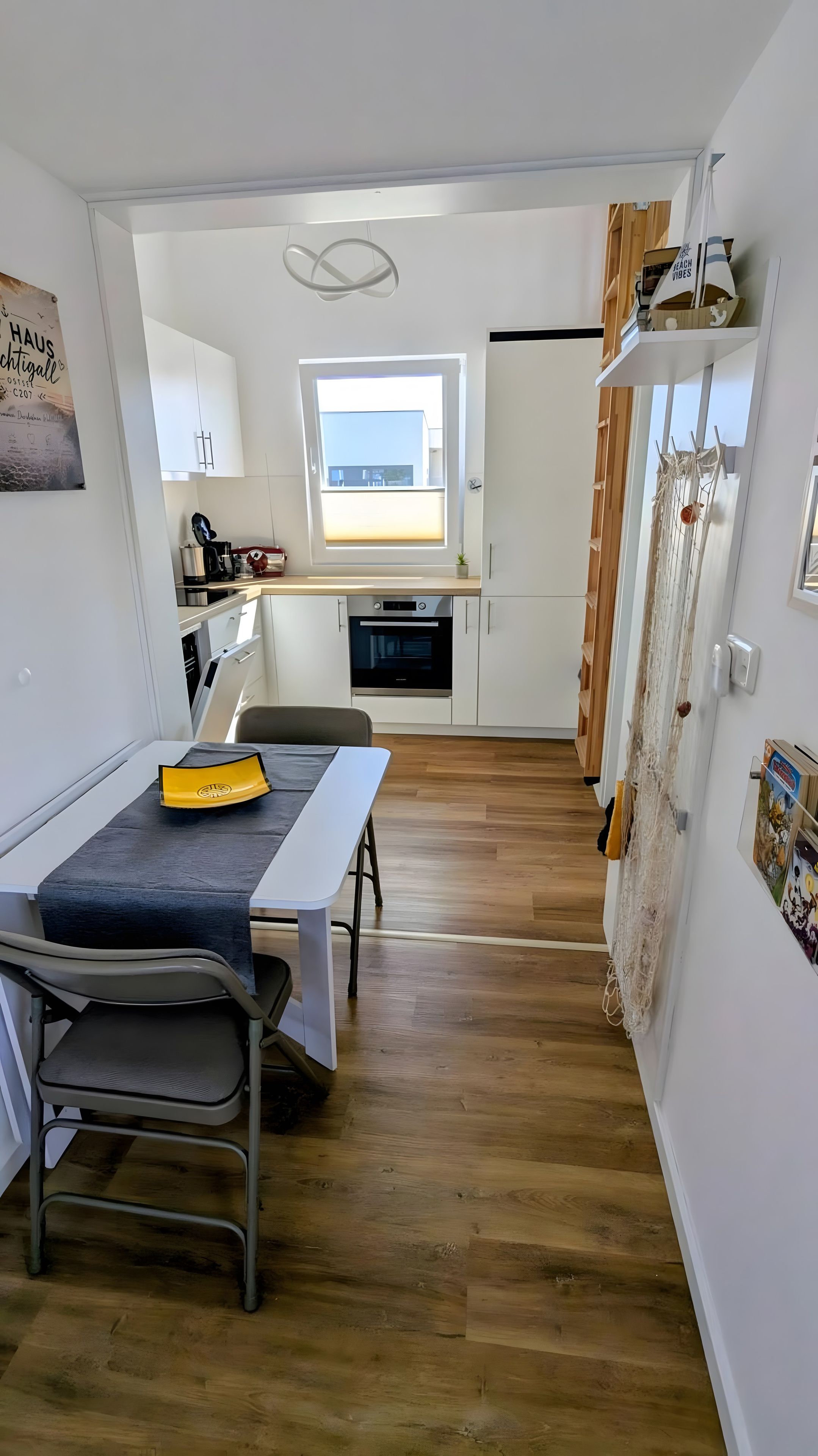 Una cocina compacta con ventana, un área de comedor con mesa y sillas, y vistas al exterior.