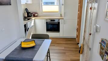 Una cocina compacta con ventana, un área de comedor con mesa y sillas, y vistas al exterior.