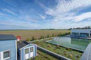 A residential property with a swimming pool, a satellite dish, and a view of a large field.