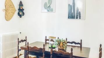 Un comedor con mesa y sillas de madera, una lámpara colgante y obras de arte en la pared.