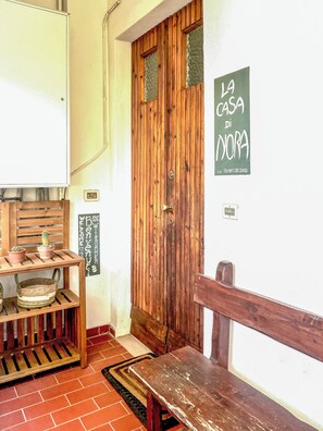 A wooden door with a sign reading 'La Casa Di Nora' and a bench to the right.