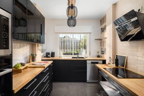 A modern kitchen with a central island, black cabinets, and a window providing natural light. - Villa Botanic | Pool | Ping Pong | Fireplace (Rincon de la victoria)