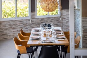 A dining area with a wooden table set for six, surrounded by wooden chairs, with a woven pendant light above. - Villa Botanic | Pool | Ping Pong | Fireplace (Rincon de la victoria)