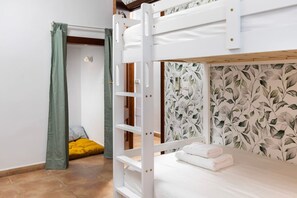 A bunk bed room with a green curtain, a yellow cushion, and a leaf-patterned wall. - Villa Selvatic | Pool | Cinema | Sauna | Mini Golf (Arenas)