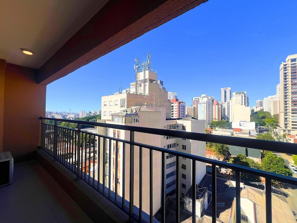 A balcony with a view of a cityscape, including high-rise buildings and a clear sky.