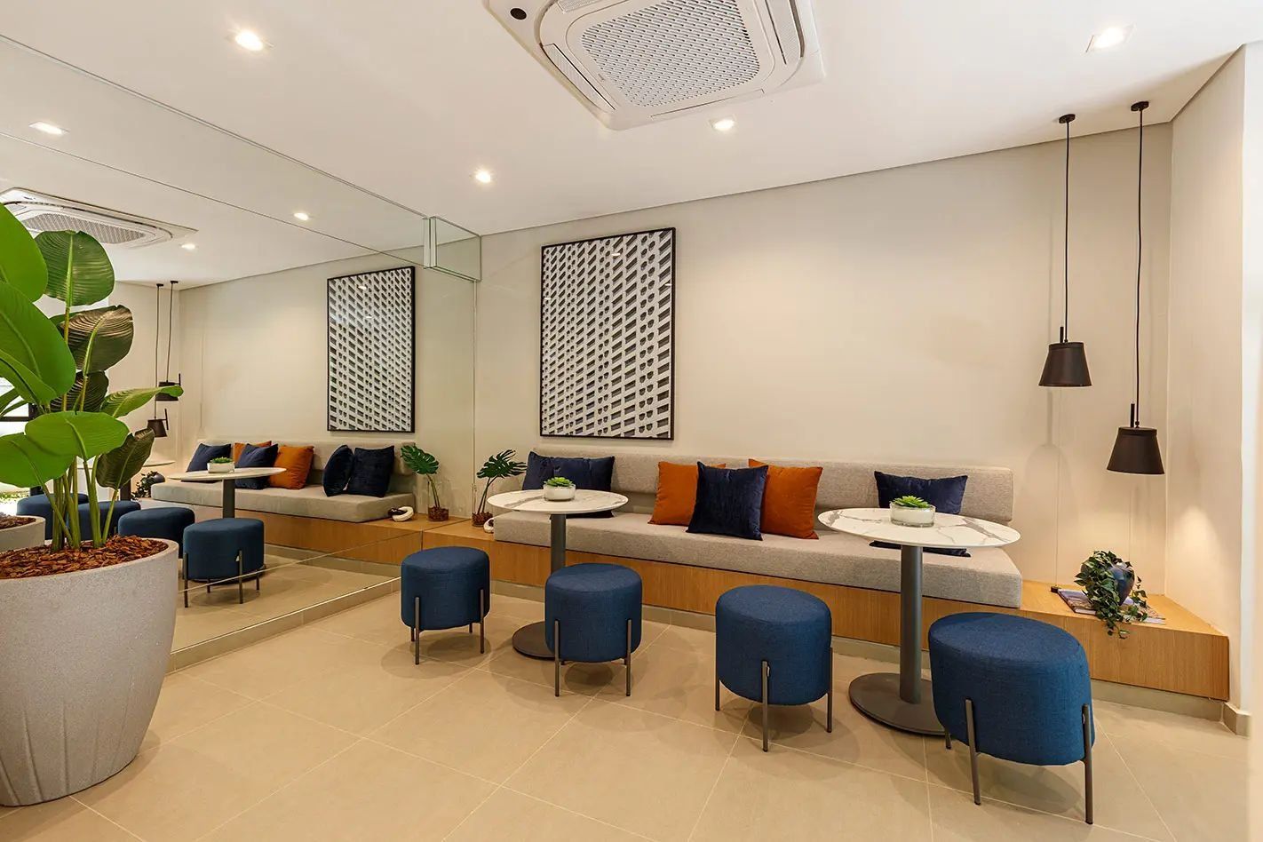 A modern lounge area with a sofa, round tables, and blue chairs.