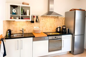 Een moderne keuken met witte kastjes, een roestvrijstalen koelkast en een betegelde spatwand.