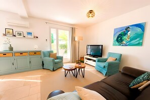 A living room with a sofa, two armchairs, a coffee table, a TV, and a painting on the wall. - Holiday home 'Lafintoux' with shared pool, Wi-Fi and air conditioning (Sablet)