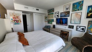 Ein Schlafzimmer mit einem großen Bett, einem Schreibtisch und verschiedenen Wandbildern.