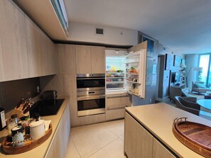 Eine moderne Küche mit eingebauten Geräten, ein Essbereich mit Tisch und Stühlen sowie ein Blick ins Freie.