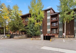 A multi-story building with a wooden facade, a covered outdoor area, and a parking lot. - NEW LISTING: Top Floor 2 Bed 2 Bath Condo. (Breckenridge)