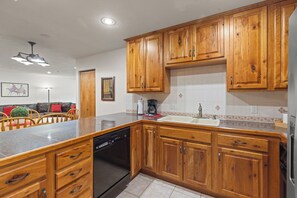 Une cuisine avec des meubles de rangement en bois, un lave-vaisselle et un plan de travail.