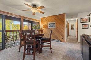 A dining area with a wooden table and chairs, a ceiling fan, and a view through large windows. - NEW LISTING: Top Floor 2 Bed 2 Bath Condo. (Breckenridge)
