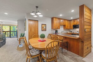 A modern kitchen with wooden cabinets, a central island, and a dining area with chairs. - NEW LISTING: Top Floor 2 Bed 2 Bath Condo. (Breckenridge)