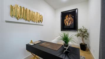 Ein modernes Interieur mit einem schwarzen Schreibtisch, einem gerahmten Kunstwerk und einem Blumentopf.