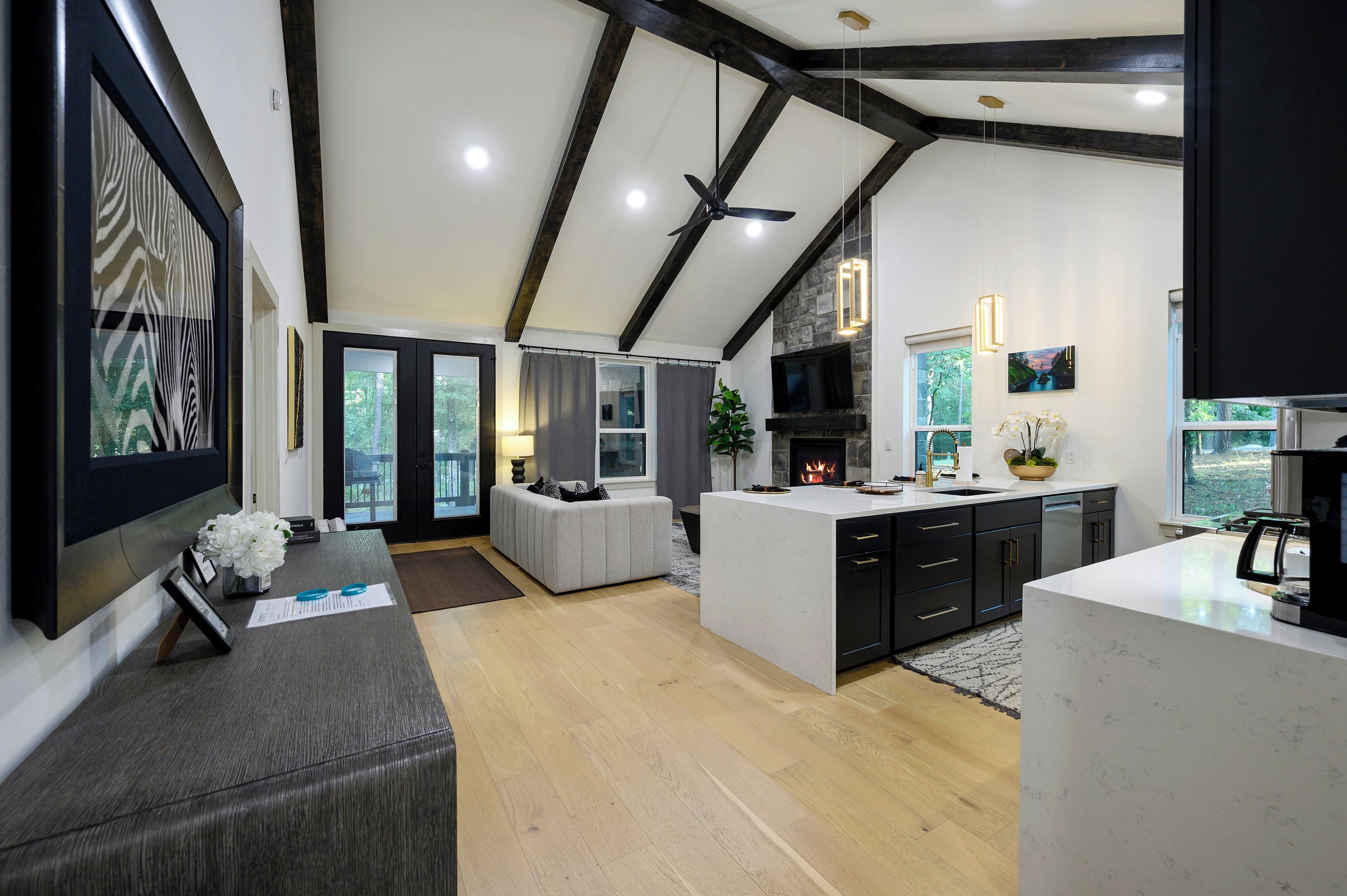 Una cocina moderna con una isla central, muebles negros y una pared decorativa de piedra.