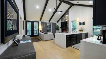 Una cocina moderna con una isla central, muebles negros y una pared decorativa de piedra.