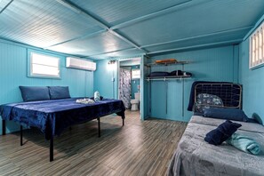 Una habitación con una litera, una cama individual, una mesa con una manta y un armario.