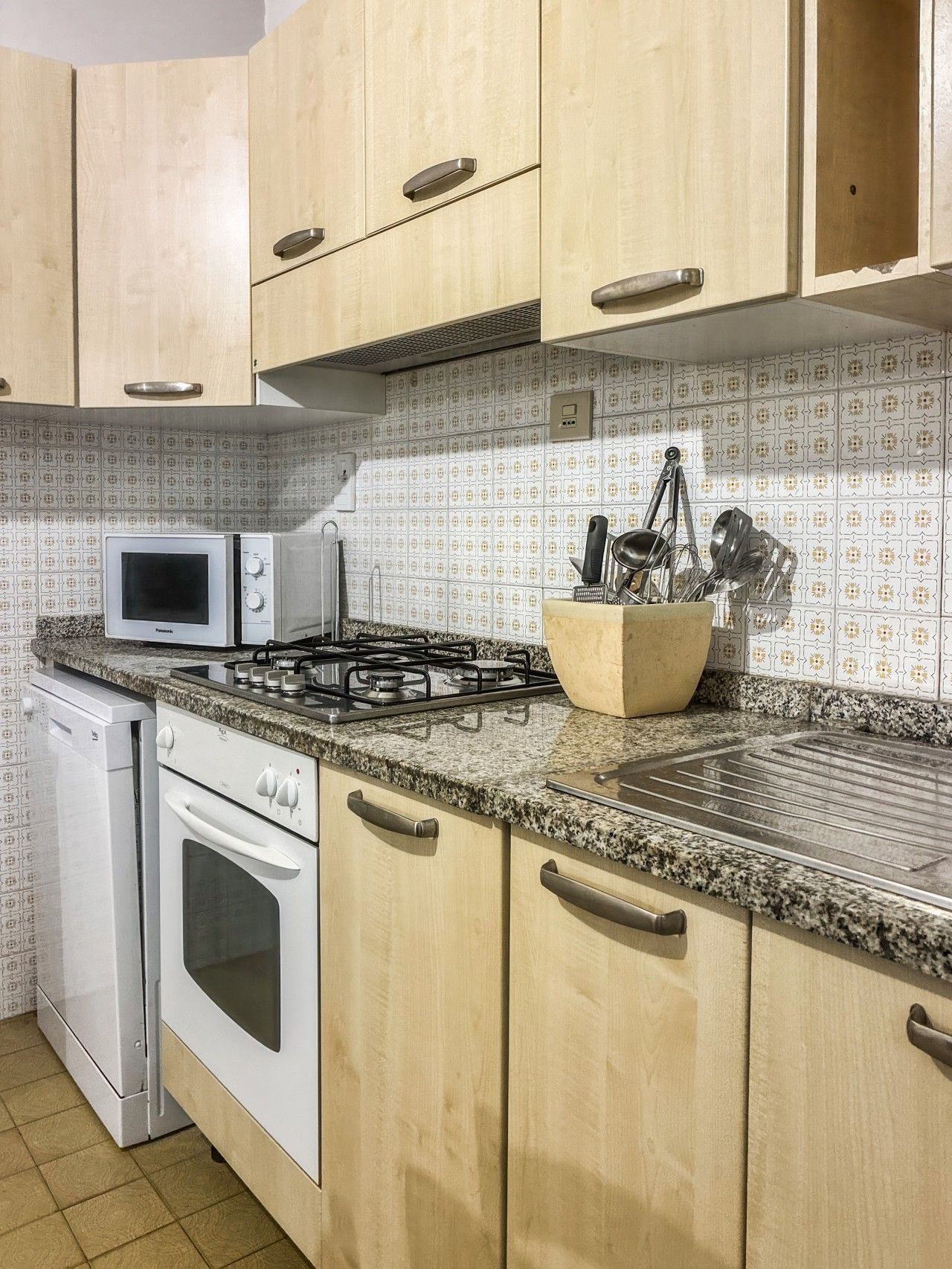 A kitchen with wooden cabinets, a microwave, a gas stove, and a dish rack.