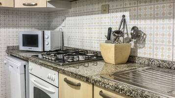 A kitchen with wooden cabinets, a microwave, a gas stove, and a dish rack.