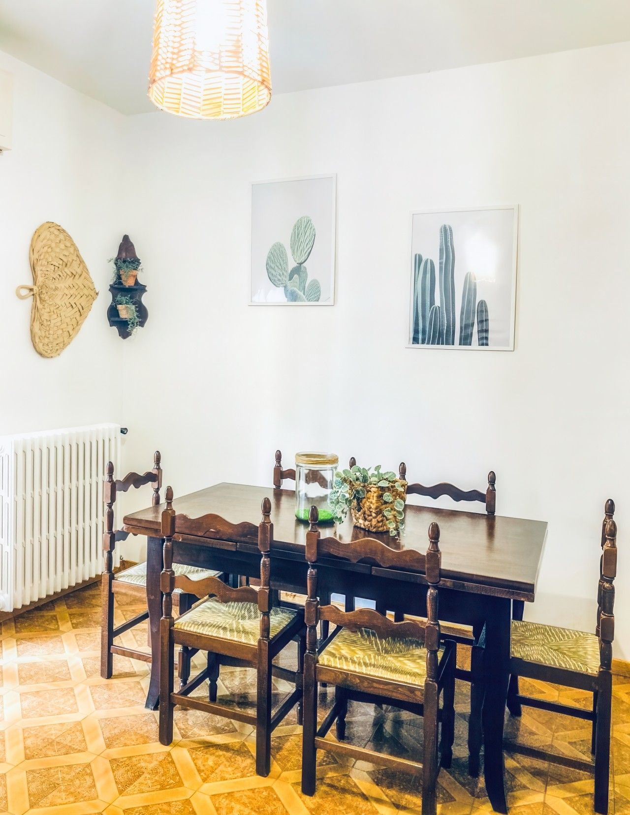 Een eethoek met een houten tafel en stoelen, een hanglamp en wanddecoratie.