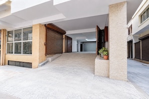 A covered outdoor area with a tiled floor, wooden shutters, and potted plants. - Classic Sector 7 Legend (New Delhi)
