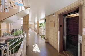 An elevator marked 2 opens right onto this floor's open-air breezeway, tile walls warmed by the afternoon sun. - Haleakala Shores A206 by Gather - Remodeled Condo Across from Kamaole Beach III (Kihei)