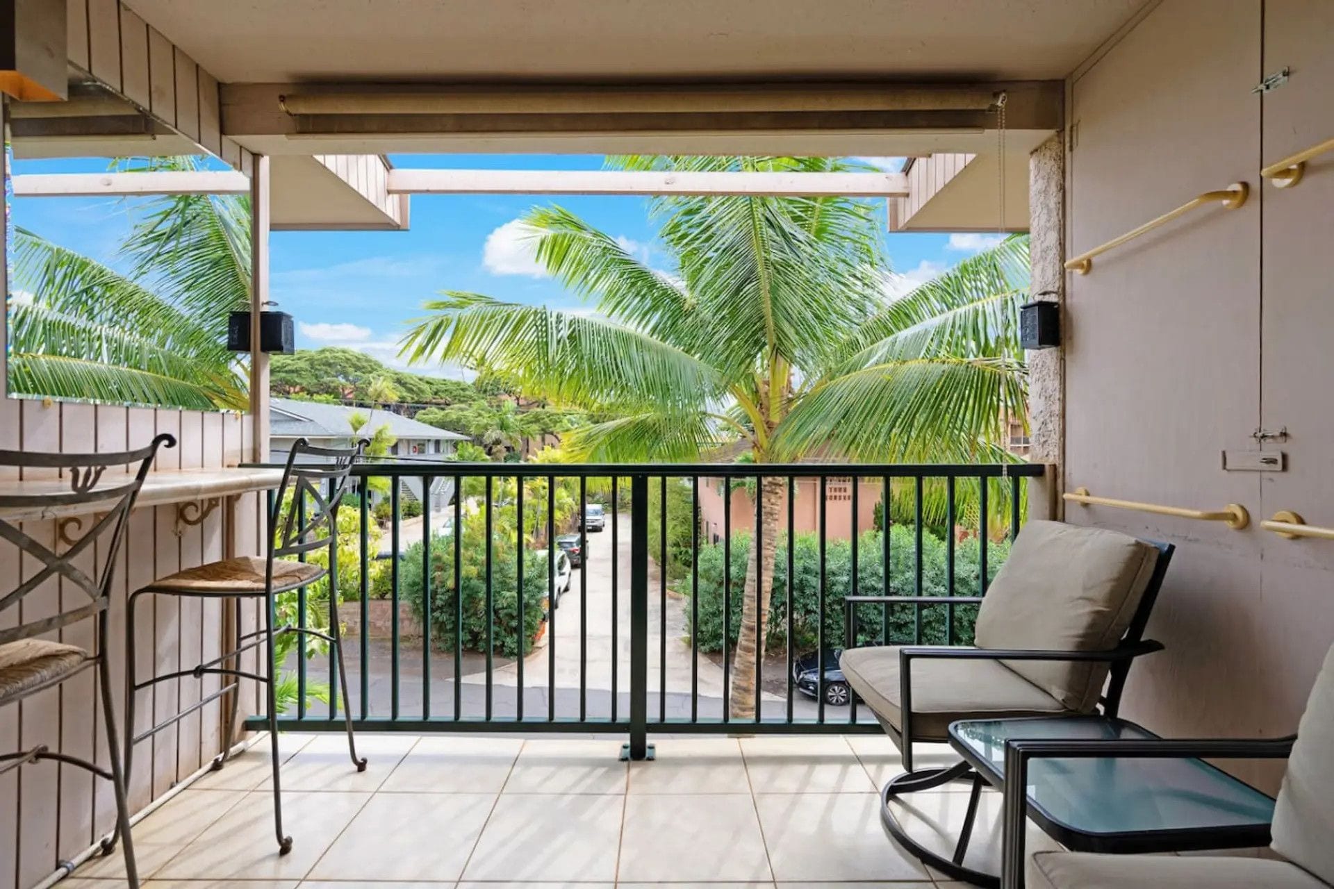 A balcony with a view of palm trees and a street.