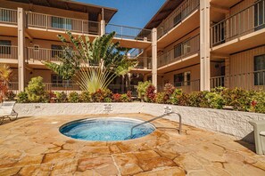A hotel pool area with a hot tub, surrounded by a stone deck and various plants. - Kihei Alii Kai C206 by Gather - Rebuilt 1BR w/ Ocean & Mountain Lanai Views (Kihei)