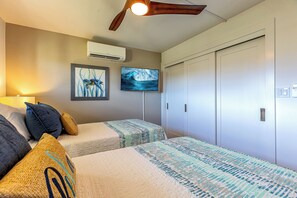 A bedroom with two beds, a ceiling fan, an air conditioning unit, and a wardrobe. - Kamaole Beach Royale 610 by Gather - Ocean View, 1 Blk to Beach, Fully AC'd (Kihei)