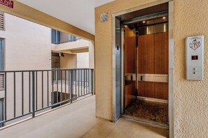 An elevator with a digital display, a wooden interior, and a metal railing outside. - Kamaole Sands 5310 by Gather - South Kihei Condo w/ Pool View & Ocean Glimpse (Kihei)