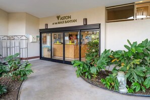 A hotel entrance with a reception desk, a metal gate, and potted plants. - Maui Banyan H306 by Gather - Ocean-View Lanai w/ AC, Walk to Beach (Kihei)