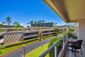 A hotel balcony with a view of a parking structure and a building with multiple floors. - Maui Banyan H306 by Gather - Ocean-View Lanai w/ AC, Walk to Beach (Kihei)