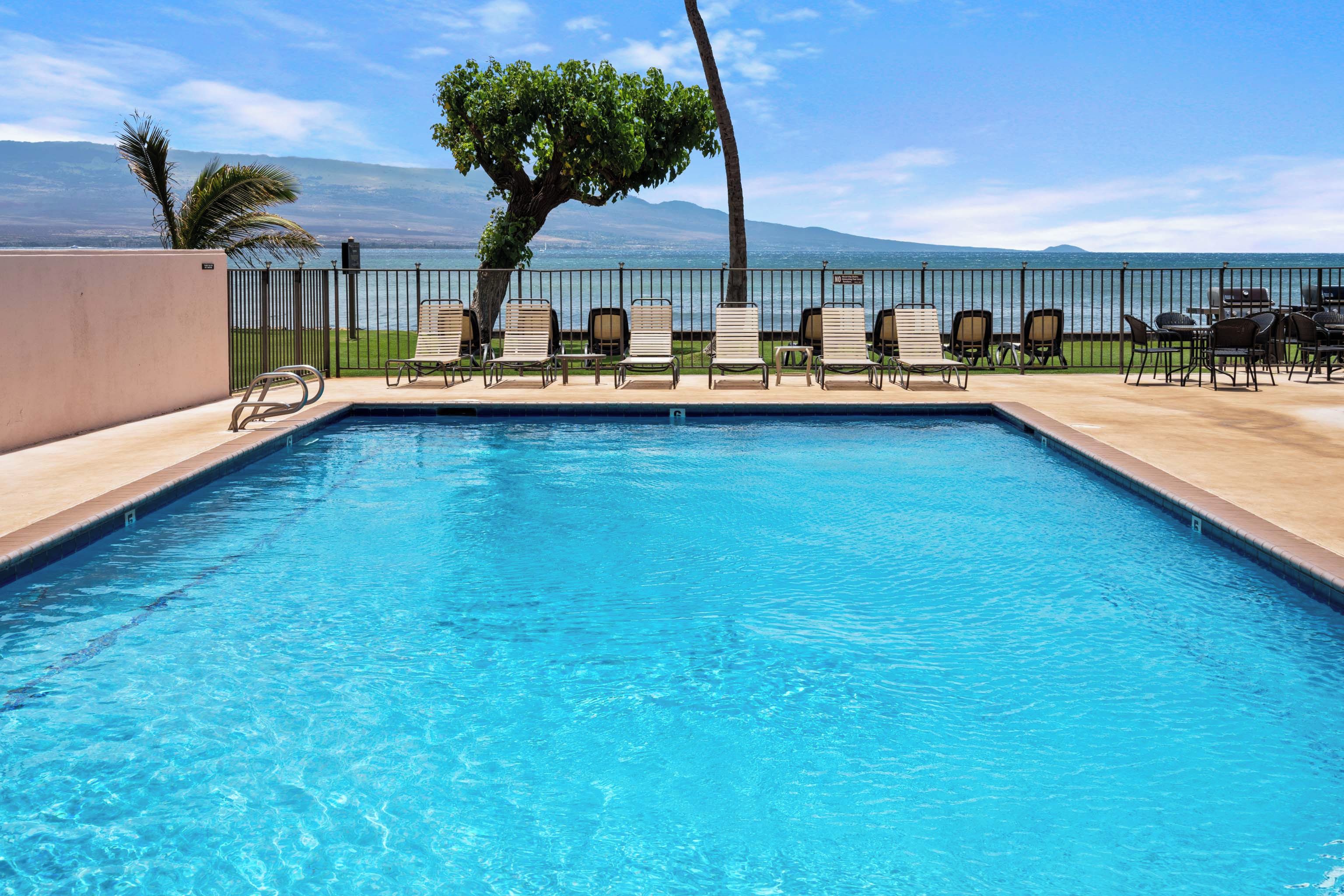 A swimming pool with lounge chairs and a view of the ocean.