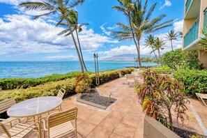 Stroll the palm-lined walkway along the water, with mountains rising across the ocean in the distance. - Punahoa Beach 205 by Gather - Oceanfront Condo w/ Private Lanai & Ocean Views (Kihei)