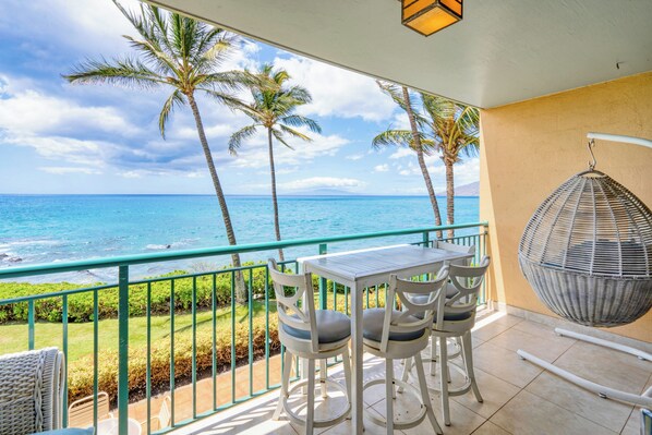 Coffee on the oceanfront lanai, where the water fills the frame past leaning palms. - Punahoa Beach 205 by Gather - Oceanfront Condo w/ Private Lanai & Ocean Views (Kihei)
