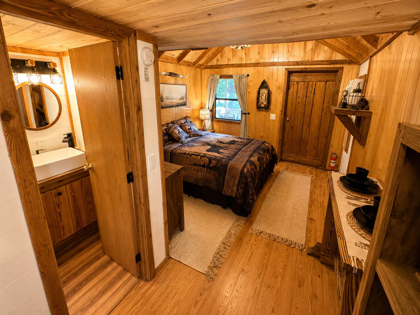 Una habitación pequeña con cama, mesita de noche, espejo y ventana.